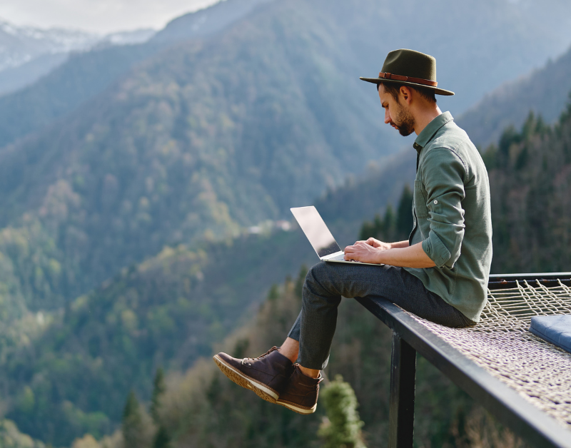 man working on laptop remotely with mountain view