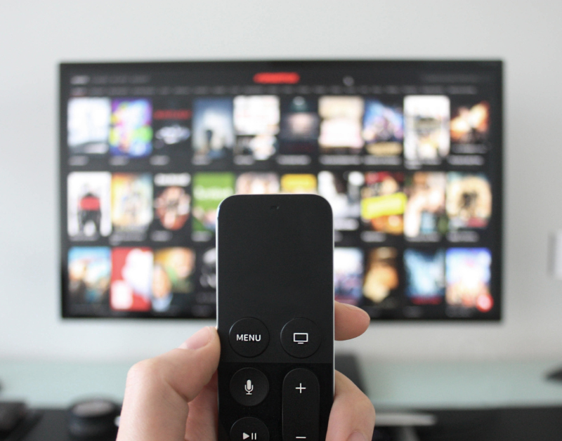 hand holding remote changing smart tv channel selecting netflix